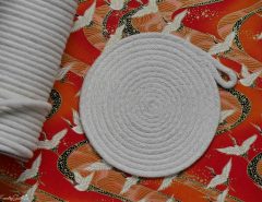 Faxco 10ft natural cotton rope coiled on a wooden table, highlighting its soft texture and triple-strand construction