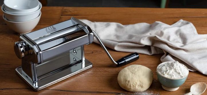 Marcato Atlas 150 chrome steel pasta roller clamped to counter rolling fresh dough sheet