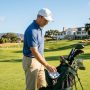 12 handicap golfer selecting a golf ball from a bag on a sunny fairway with a golf course in the background