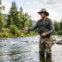 An angler wearing a wide-brim UPF 50 fishing hat while standing in a river fly fishing