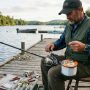 An angler spooling a spinning reel with monofilament fishing line on a wooden dock