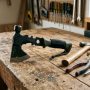 A compact multi-purpose survival axe resting on a wooden workshop bench next to basic home repair tools