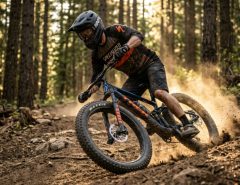A cyclist riding a fat tire mountain bike on a sunlit dirt trail.