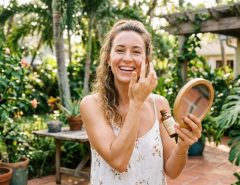 Woman applying anti-aging facial serum outdoors in sunny Florida.