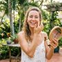 Woman applying anti-aging facial serum outdoors in sunny Florida.