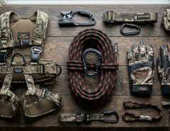 A coiled hunting rope with a carabiner neatly arranged next to safety gear.