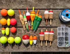 Assorted fishing floats and bobbers arranged on a wooden table.