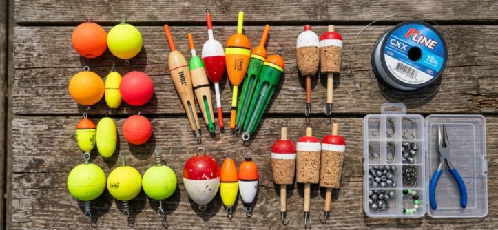 Assorted fishing floats and bobbers arranged on a wooden table.