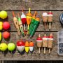 Assorted fishing floats and bobbers arranged on a wooden table.