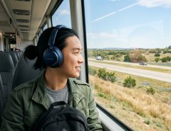 Traveler wearing Soundcore over-ear headphones looking at Texas scenery from a window.