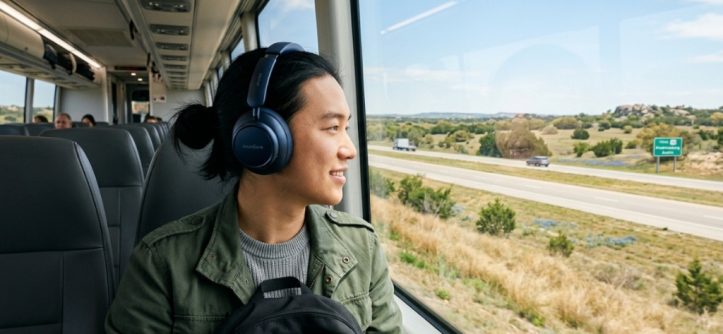 Traveler wearing Soundcore over-ear headphones looking at Texas scenery from a window.